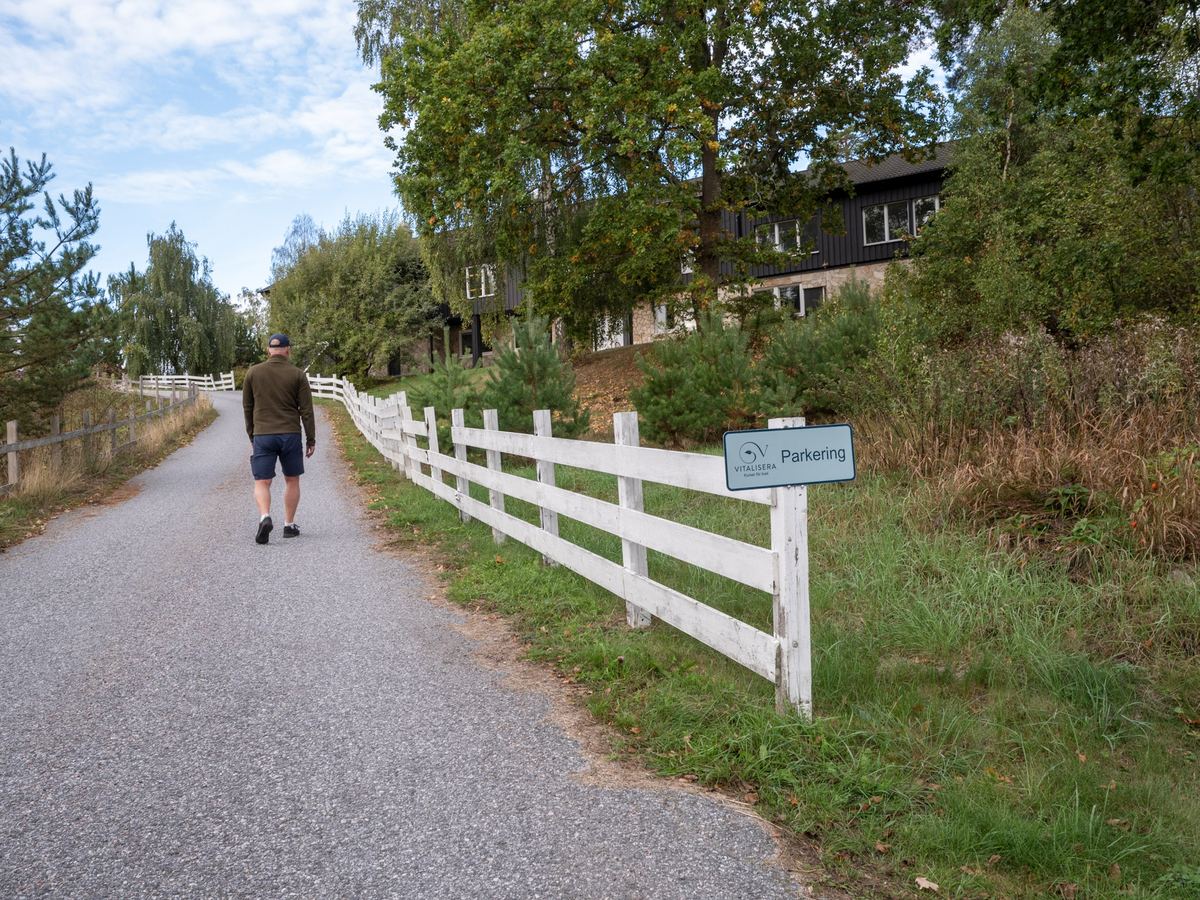 En person går längs vägen förbi ett vitt staket.