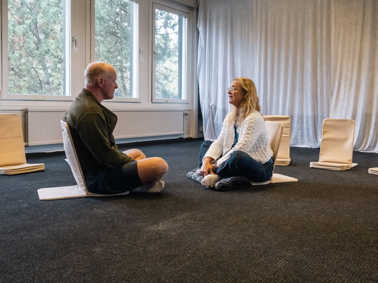 Två deltagare sitter på golvet mitt emot varandra och samtalar.